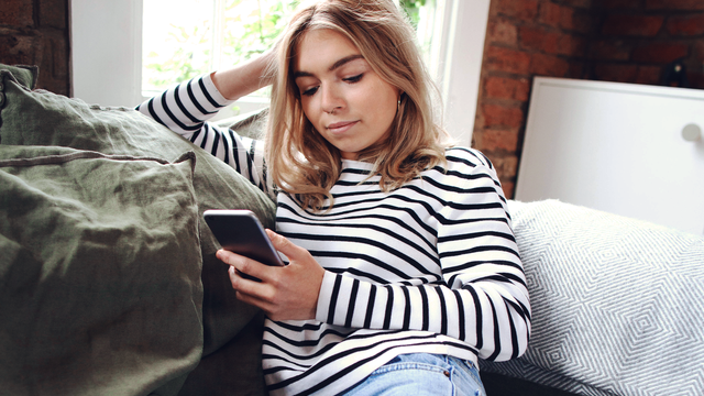 A woman in a striped shirt looking at her phone